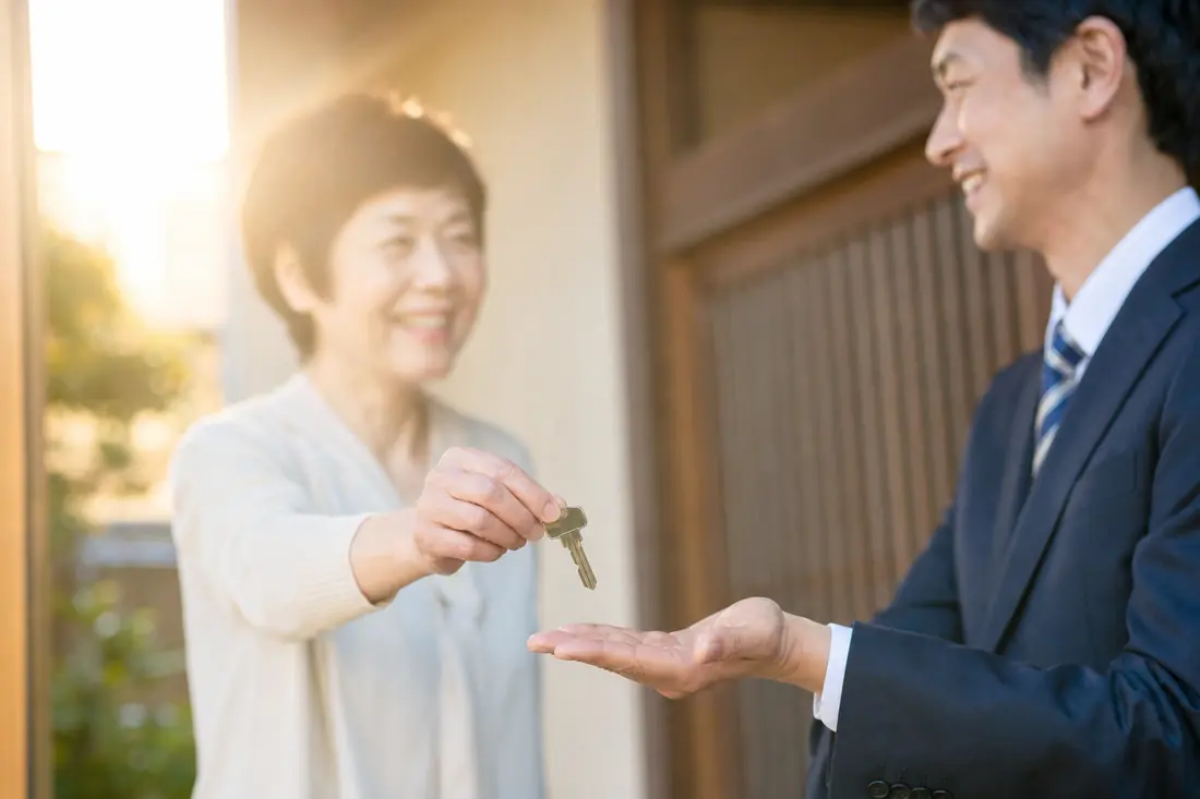 玄関先で家の鍵を受け渡す手元